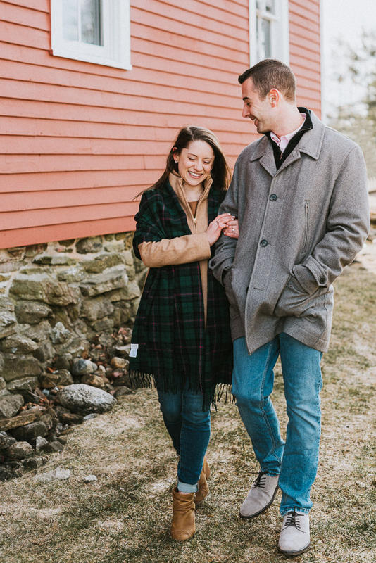 A man and woman walk arm in arm alongside Jacobson Barn during their UConn engagement session.