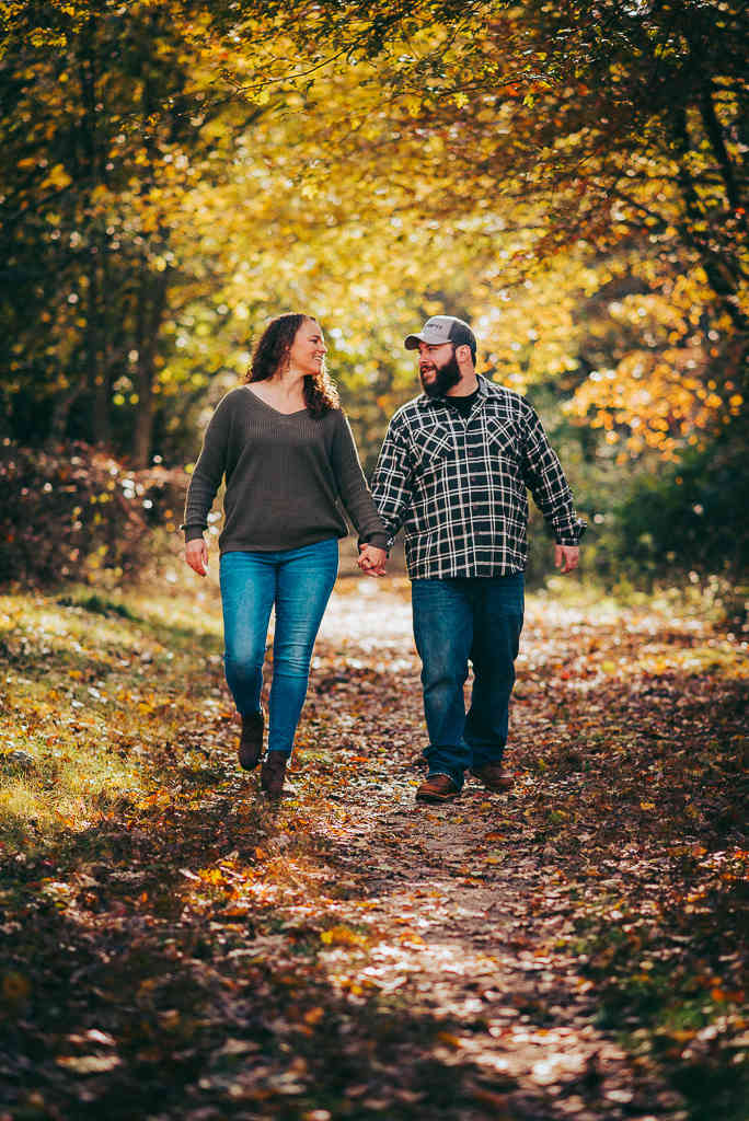 Engaged couple walking among foliage during their Haley Farm engagement session.