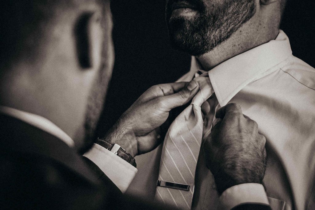 A groom has his tie straightened by his best man in preparation for his Rhode Island wedding.
