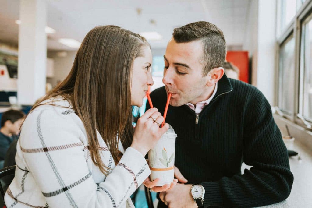 An engaged couple shares a milkshake with red straws during their UConn engagement session.