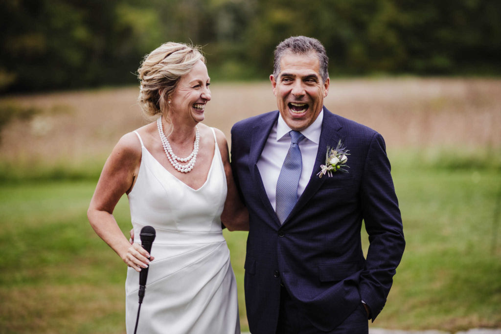 A bride and groom speak into a microphone during their Stone Acres Farm wedding.