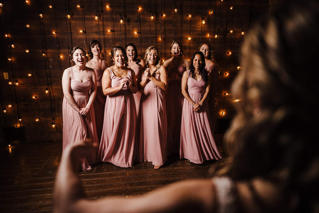 A bride surprises her bridesmaids at one of the best wedding venues in Connecticut, The Barns at Wesleyan Hills.