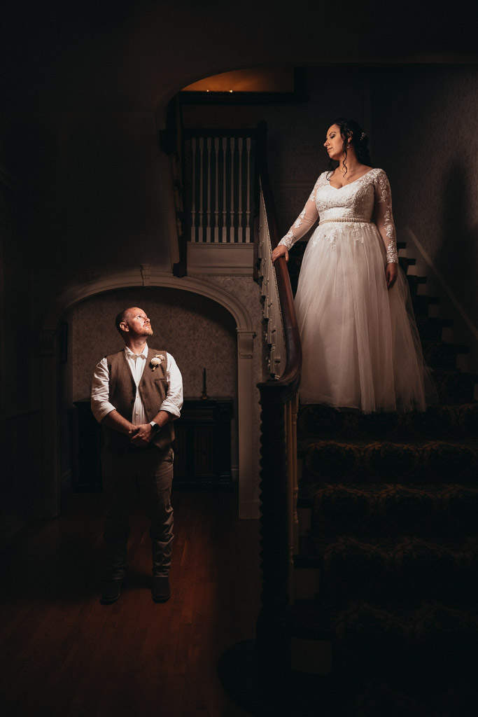 A bride and groom pose in the foyer during their Haley Mansion wedding.