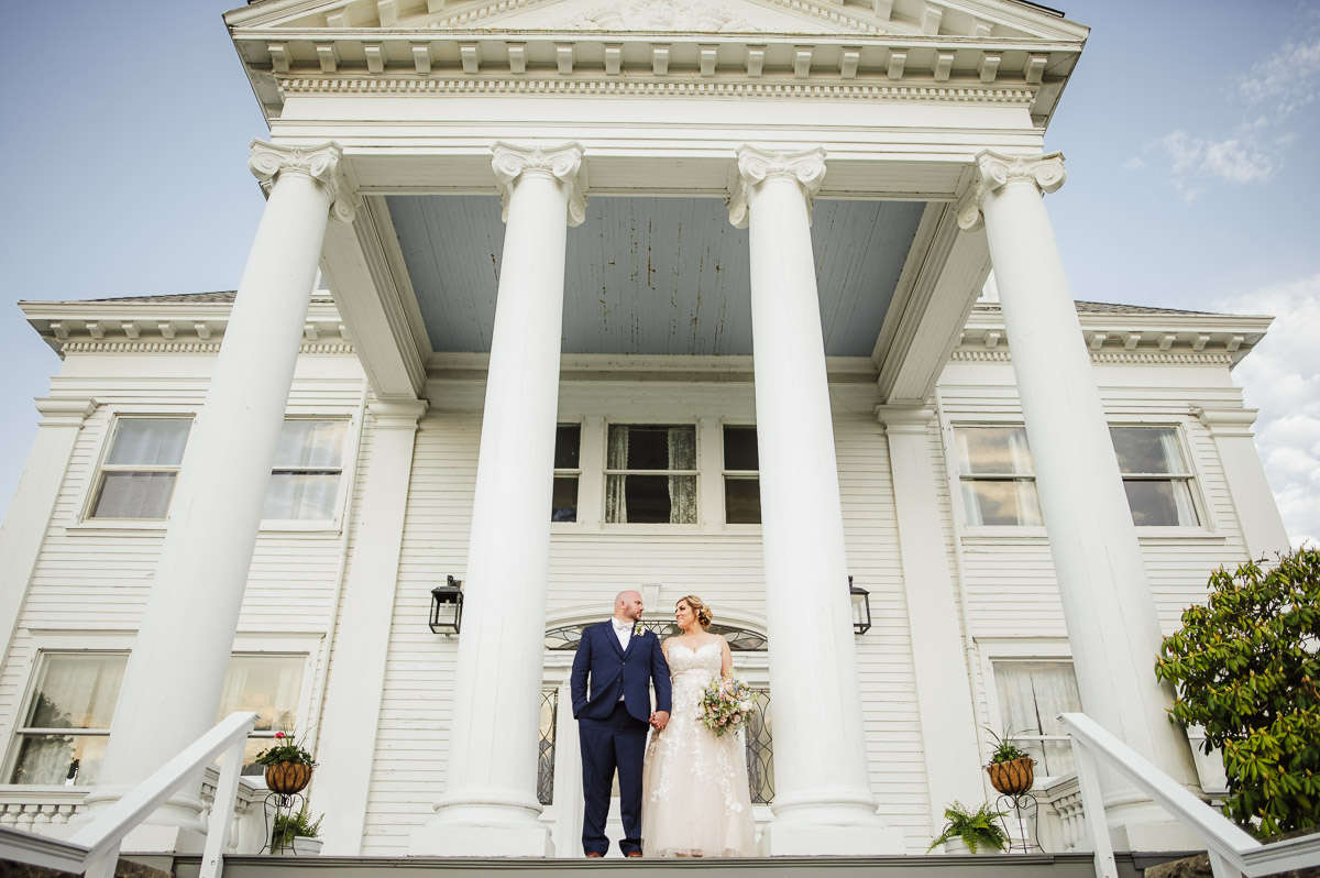 A bride and groom stand on the exterior landing of Haley Mansion during their Mystic, CT wedding at Inn at Mystic.