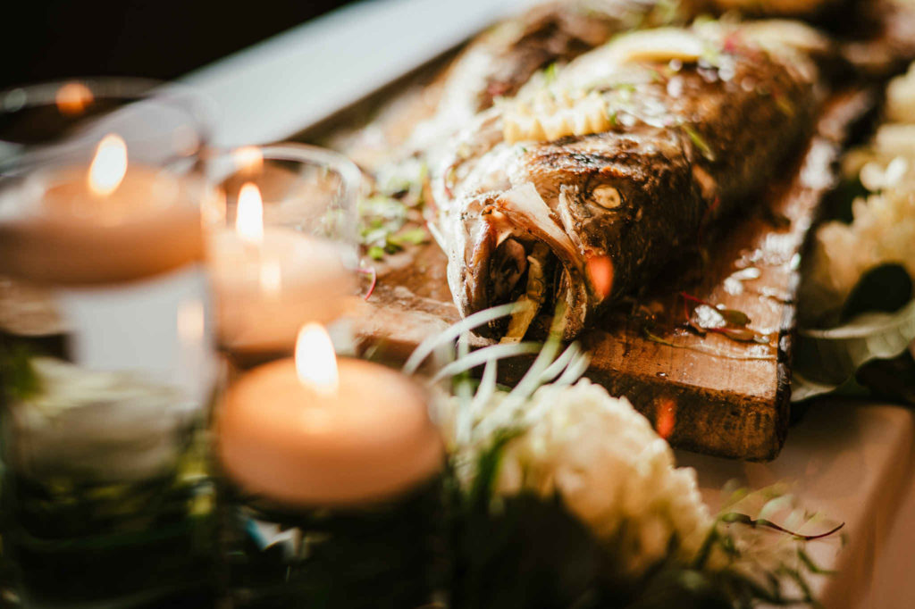 Candles are next to a fried fish during a Branford House wedding.