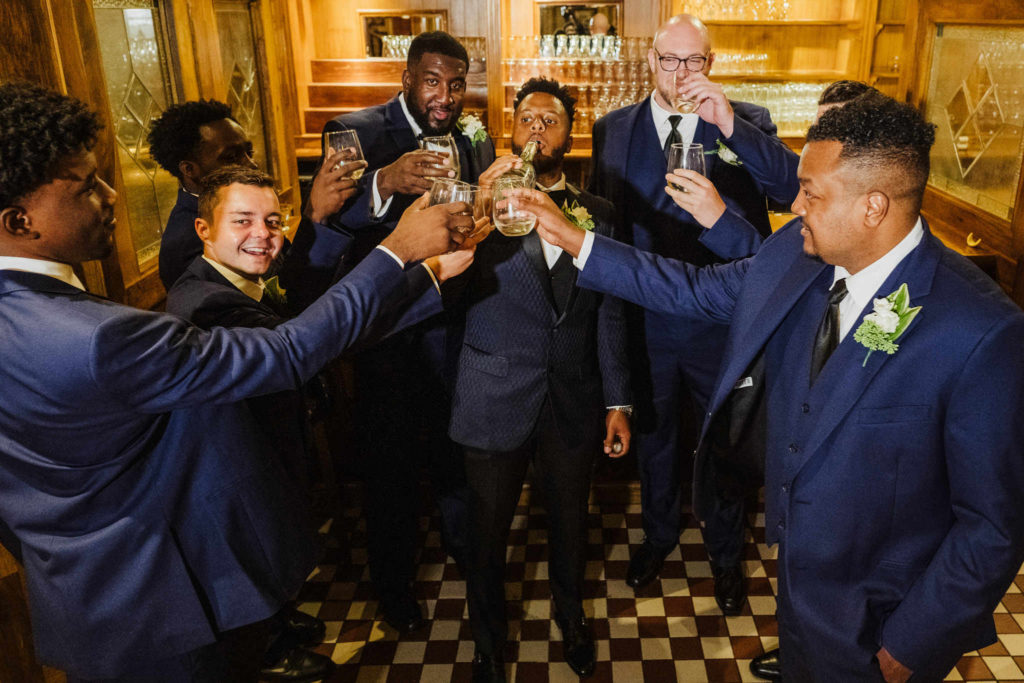 A groom and groomsmen celebrate with champagne during this wedding at The Society Room of Hartford.