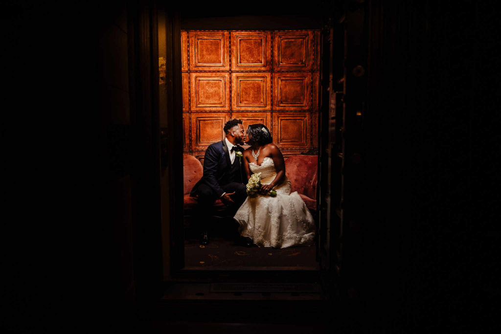 A bride and groom kiss while sitting inside a former bank vault at The Society Room of Hartford during their Hartford wedding.
