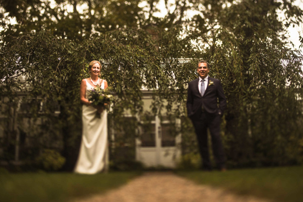Bride and groom in front of a greenhouse during their Stone Acres Farm wedding.