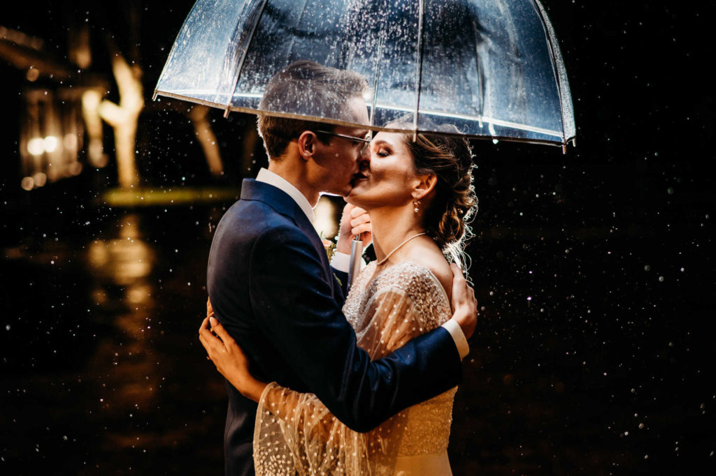 Wedding photo of couple under umbrella at night.