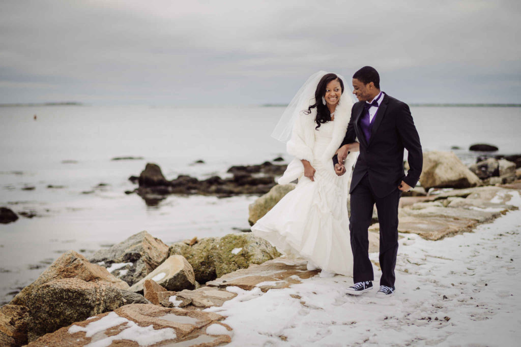A bride and groom walk in the snow at their Stonington, CT wedding venue.