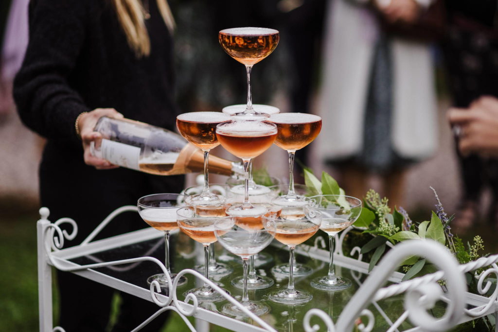 A Connecticut wedding day-of coordinator helps to pour pink sparkling wine for reception guests.