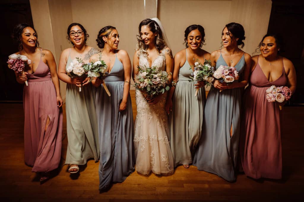 Bridesmaids in Azazie bridesmaid dresses smile and laugh with the bride.
