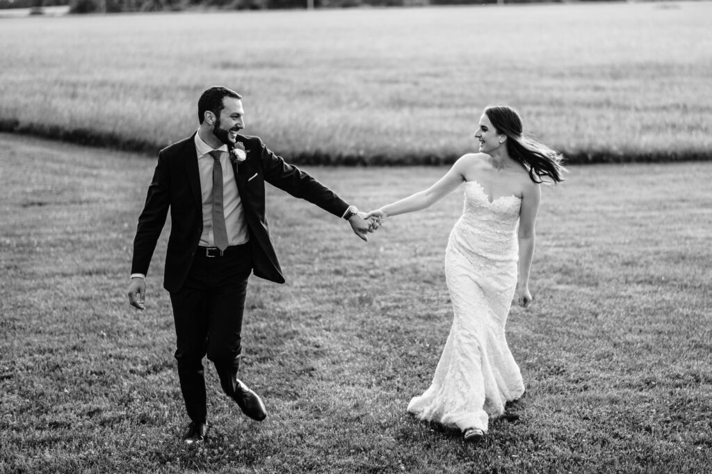 A couple holds hands and runs during their Lion Rock Farm wedding.