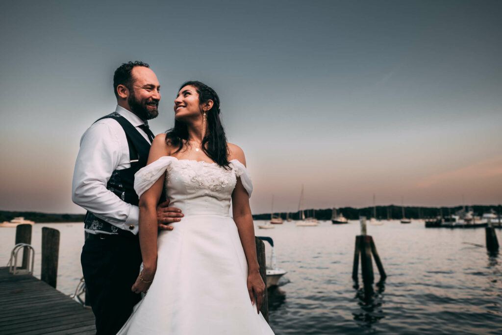 A couple poses in front of the CT River during their Connecticut River Museum wedding.