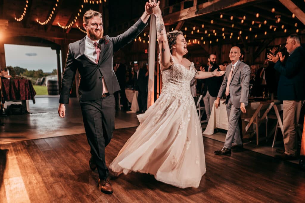 A bride and groom walk into their rustic barn reception and are captured by their wedding photographer.