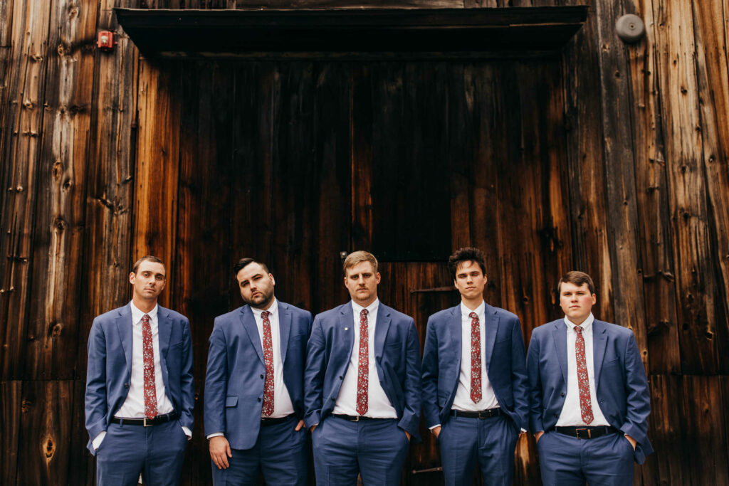 Groomsmen pose in front of Webb Barn during a wedding at the Webb Deane Stevens Museum.