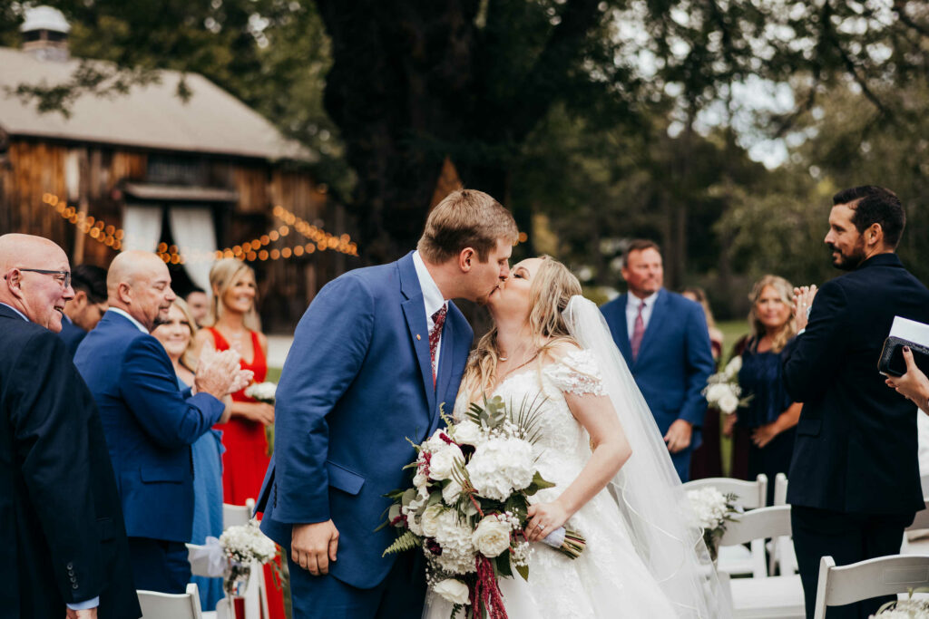 A bride and groom enjoy their first kiss at the end of their ceremony at Connecticut barn wedding venue Webb Barn.