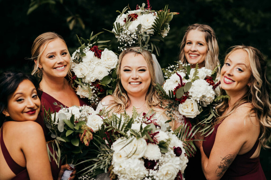 A bride is surrounded by her bridesmaids' bouquets during a Webb Barn wedding at the Webb Deane Stevens Museum.