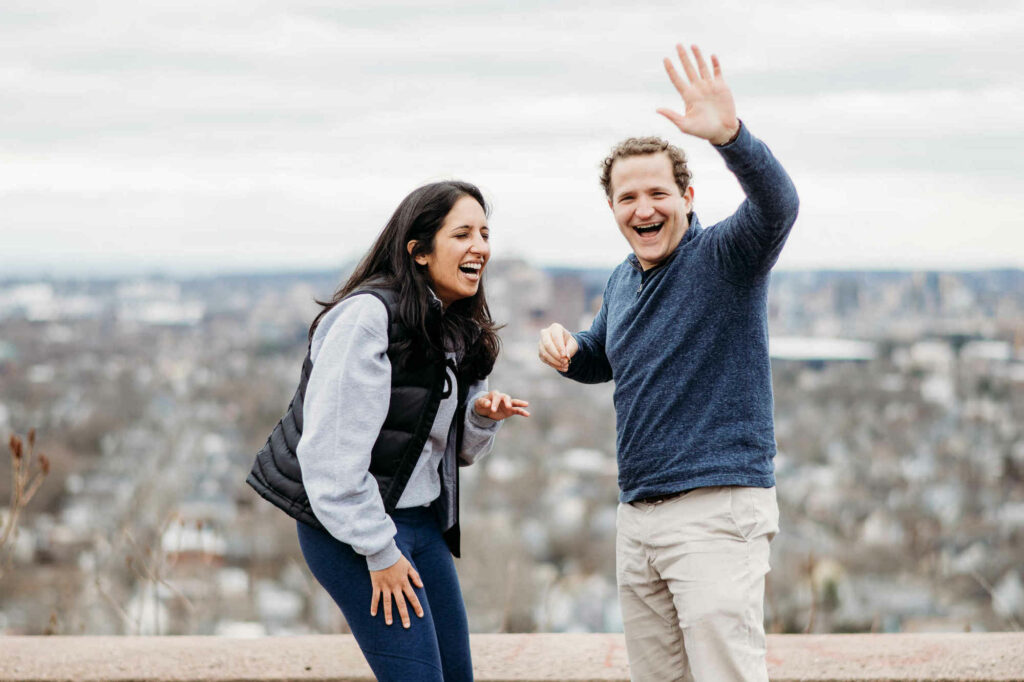 After proposing at East Rock Park in New Haven, Survivor contestant Daniel Strunk waves to the camera as his fiancé laughs.