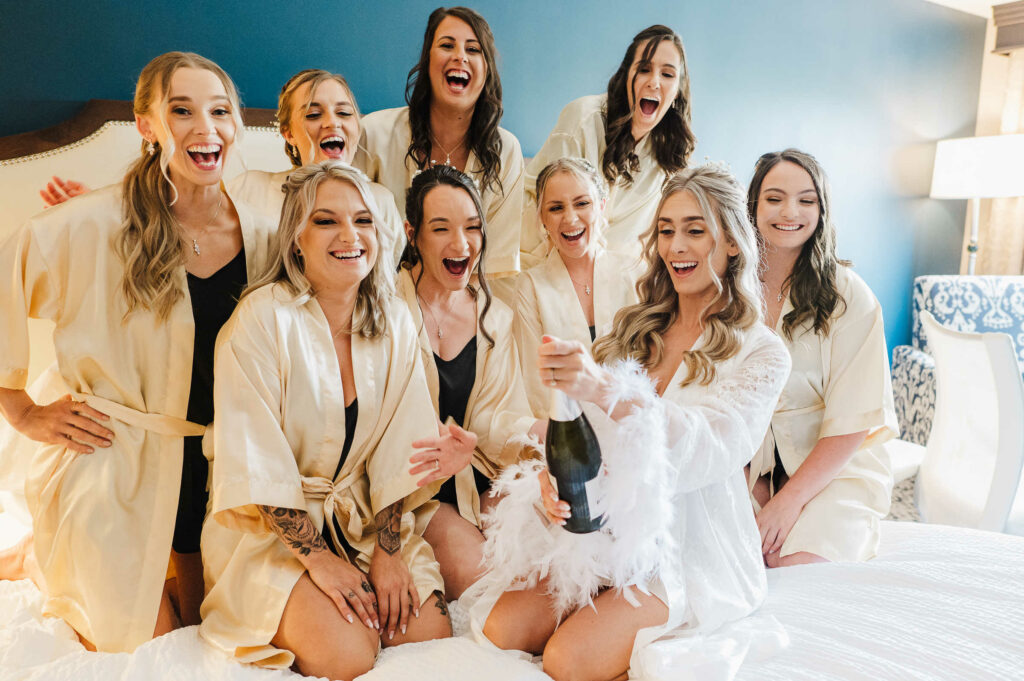 A bride and her bridesmaids open a bottle of champagne before her Portland CT wedding.