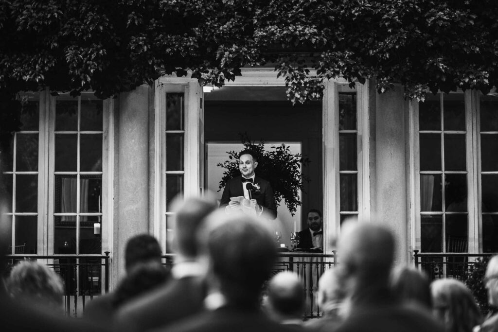 A groomsman gives a speech from the balcony of the Terrace Room of The Lord Thompson Manor.