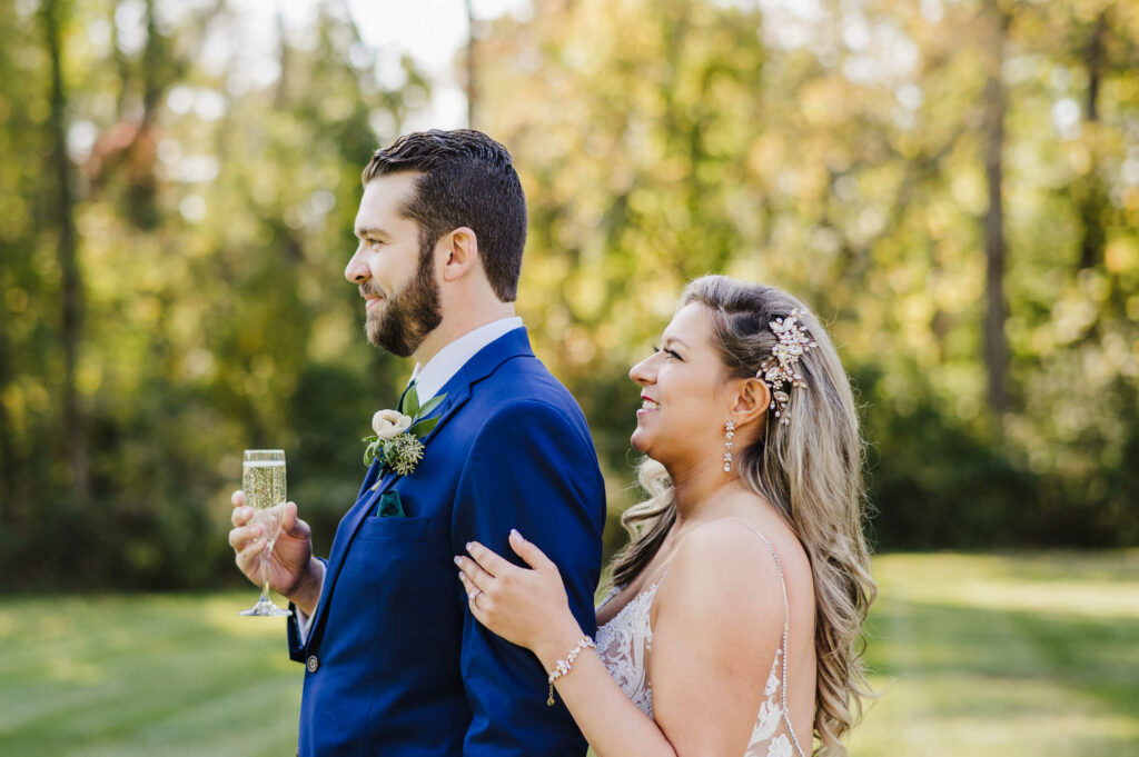 A bride and groom hug and smile with champagne before their Connecticut mansion wedding.