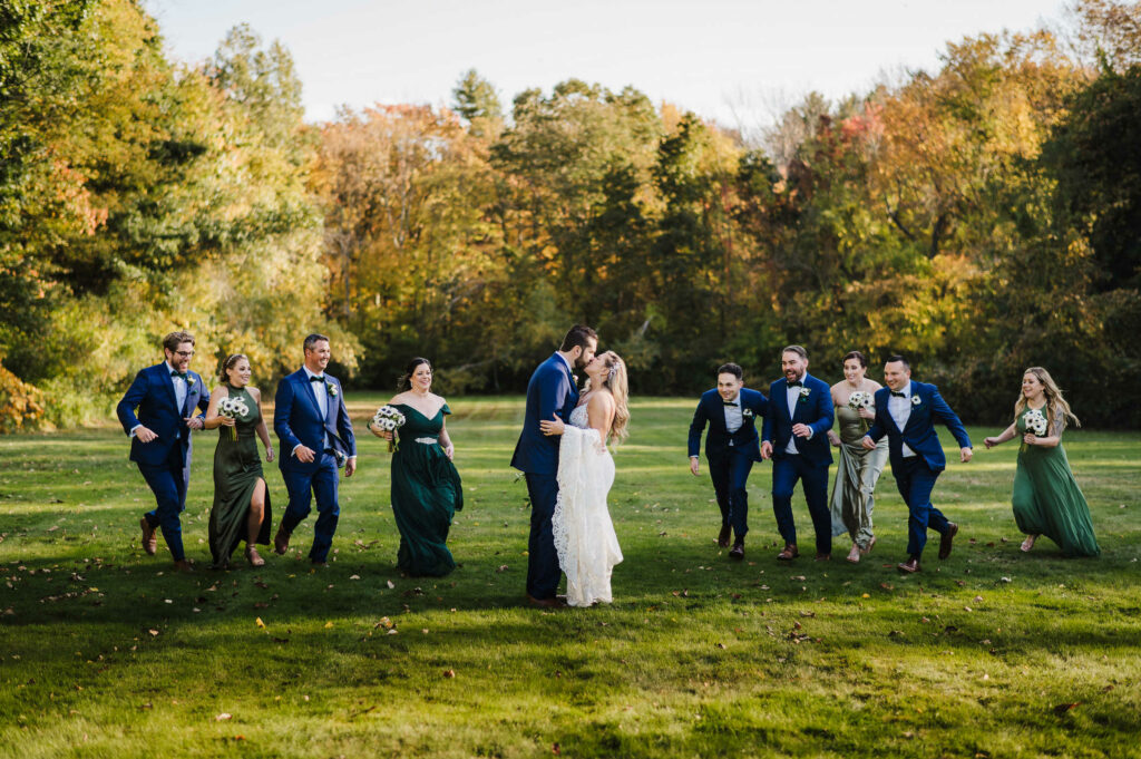 The wedding party runs at the bride and groom during their Connecticut mansion wedding.