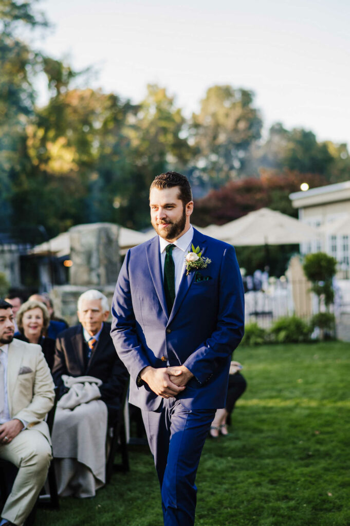 The groom walks down the aisle for the ceremony of his Connecticut mansion wedding.