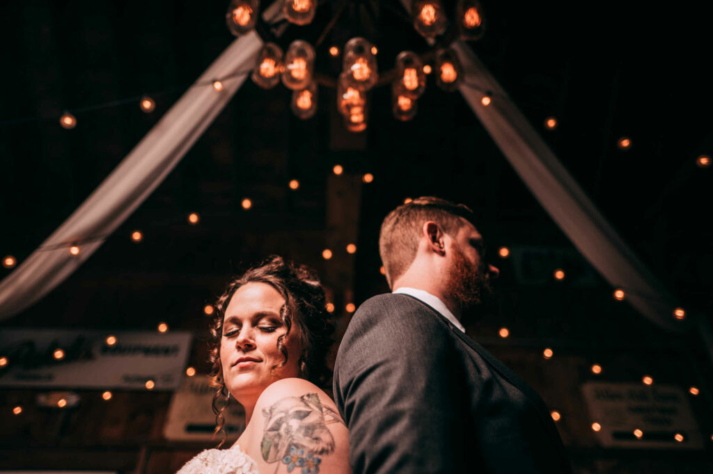 A bride and groom pose together underneath a mason jar chandelier during their Allen Hill Farm wedding.