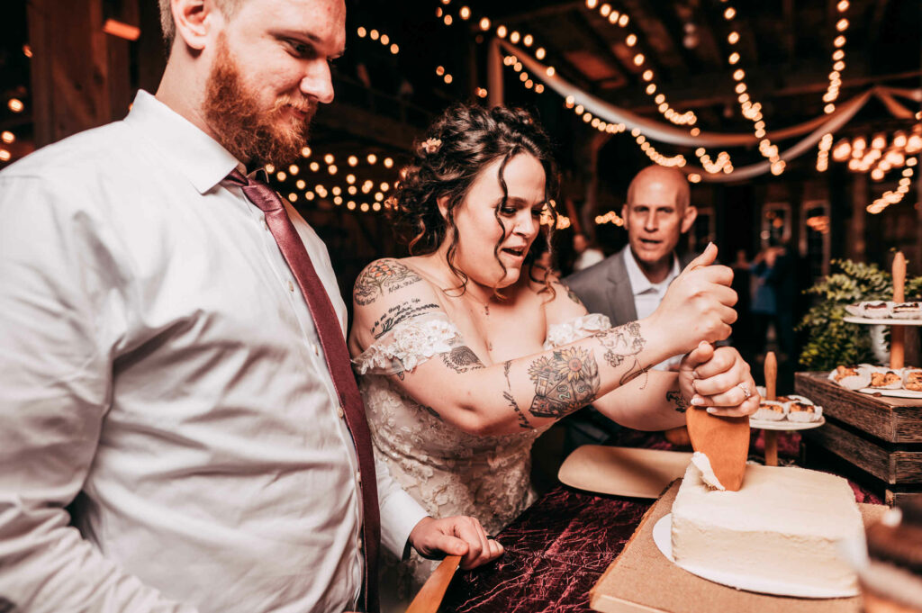 The bride and groom cut their cake during the reception of their Allen Hill Farm wedding.
