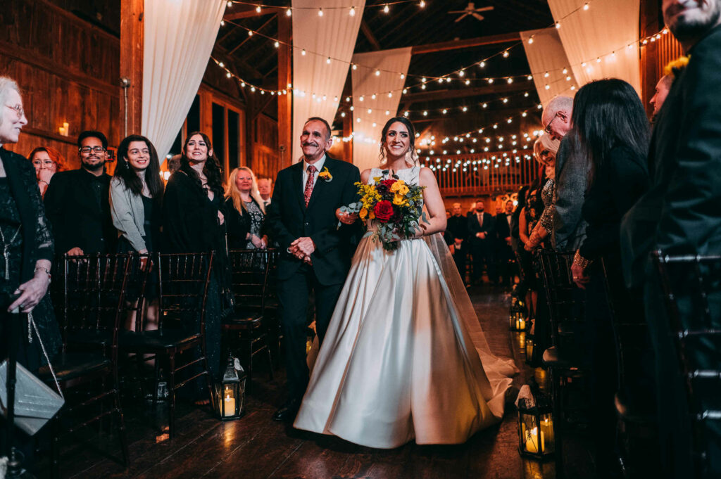 The bride is walked down the aisle by her father at The Barns at Wesleyan Hills, one of Connecticut's best barn wedding venues.