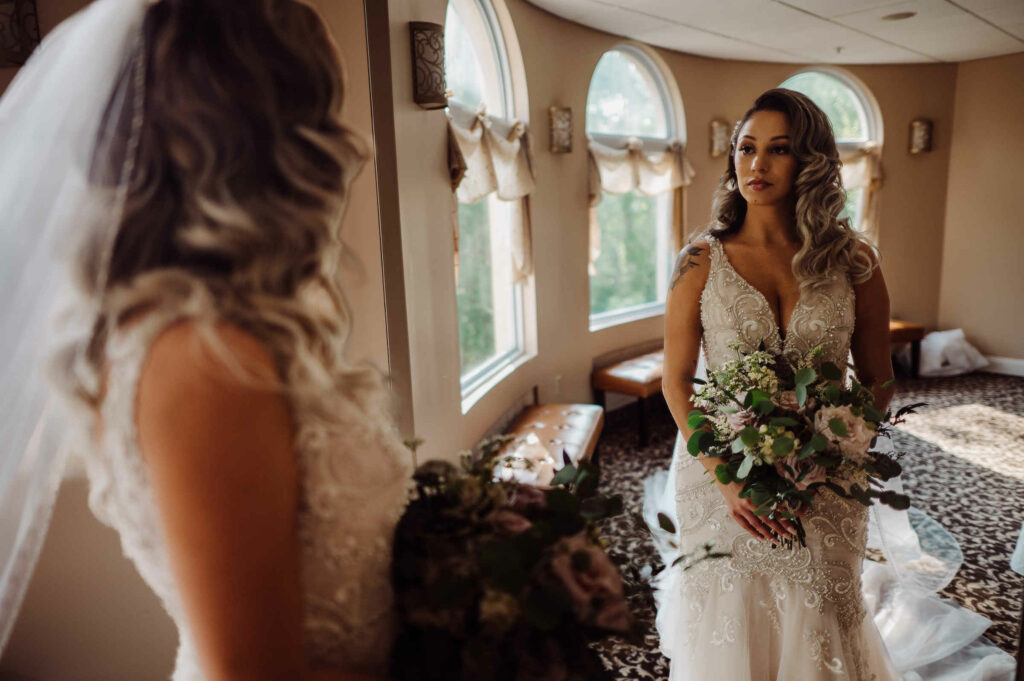 A bride looks at herself in the mirror of the getting ready suite before her Cascade wedding.