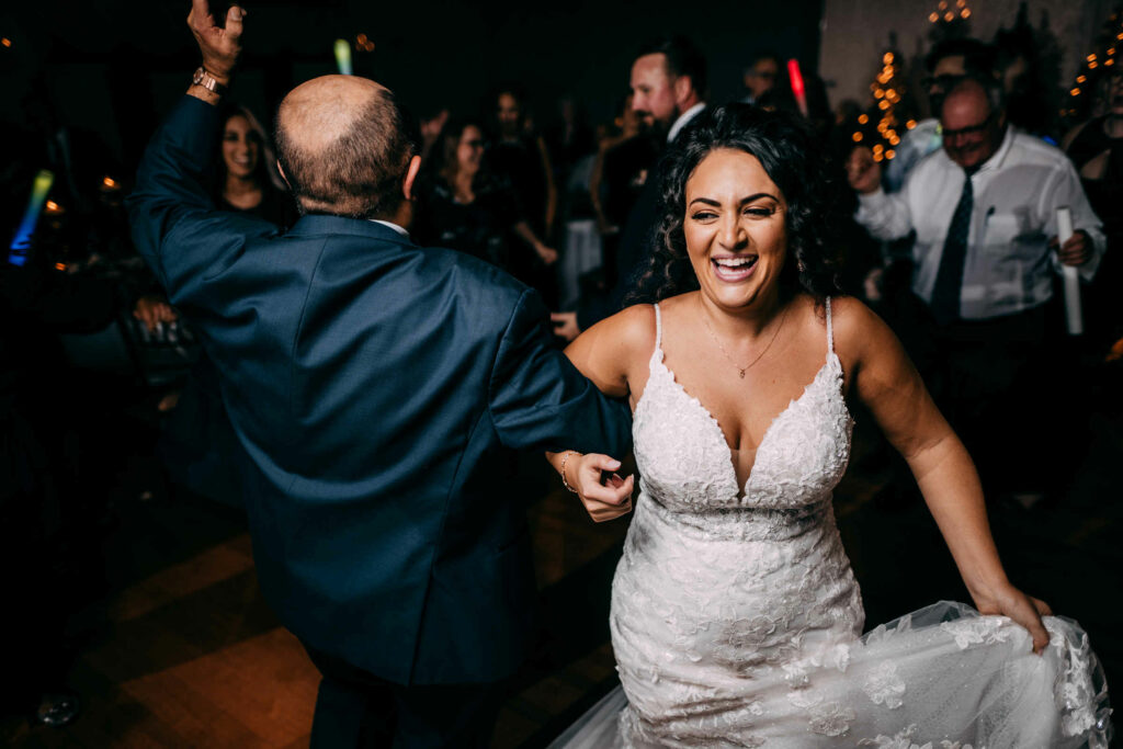A bride dances with her father while wearing at big smile at her Cascade Hamden wedding.