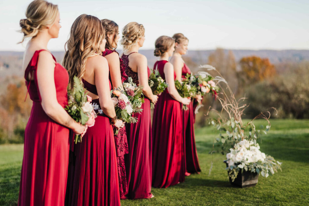Bridesmaids in red dresses stand in a row during a Lyman Orchards wedding ceremony.