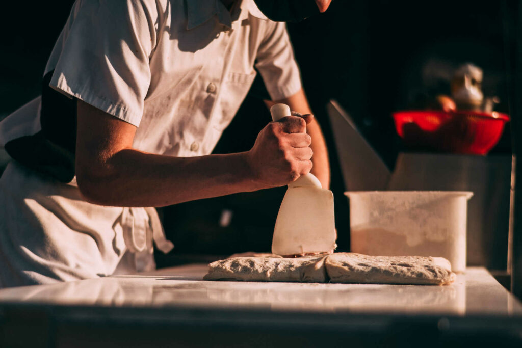 A great example of food truck catering in Connecticut, a chef for Victoria's prepares pizza dough for a rustic wedding.