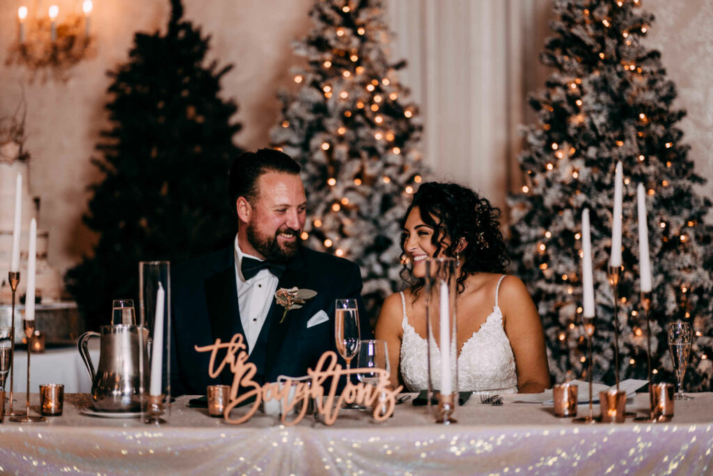 A couple sits at their sweetheart table during their wedding at Cascade Fine Catering.