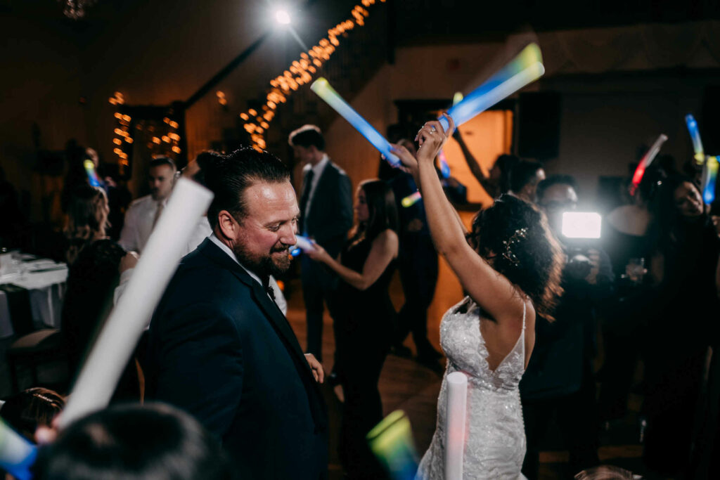 A bride and groom dance with foam light sticks during their New Haven banquet hall wedding.
