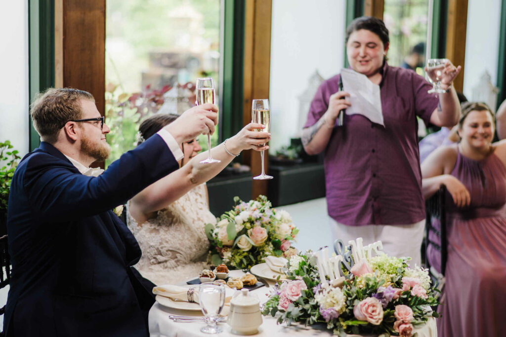 The maid of honor toasts the bride and groom during their Pond House Café wedding.