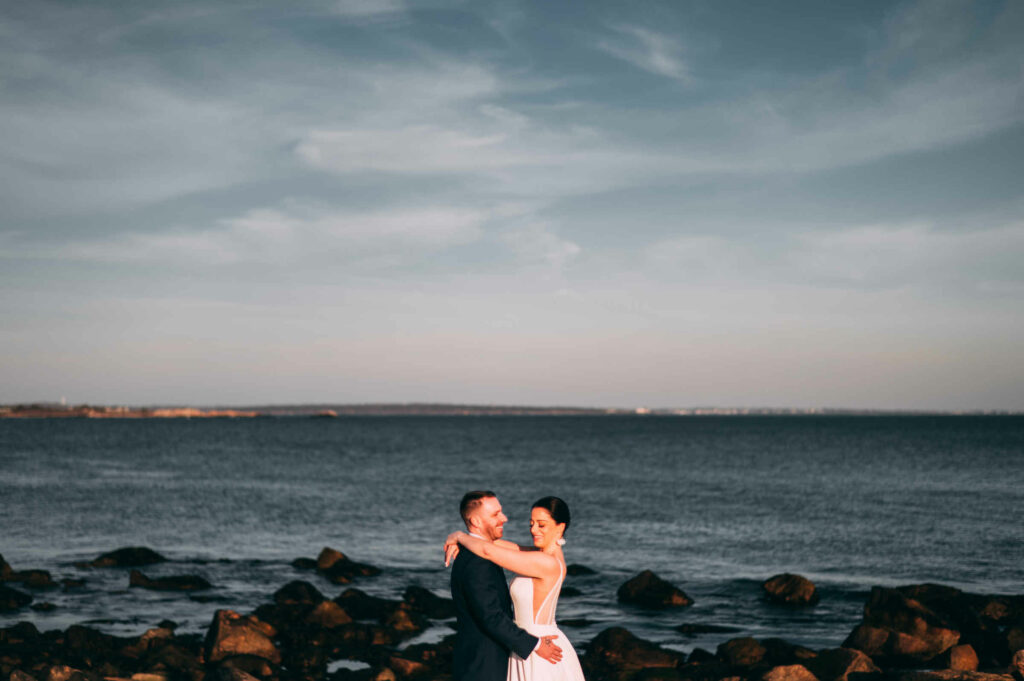 A bride and groom embrace outside their Rhode Island wedding venue in Narragansett.