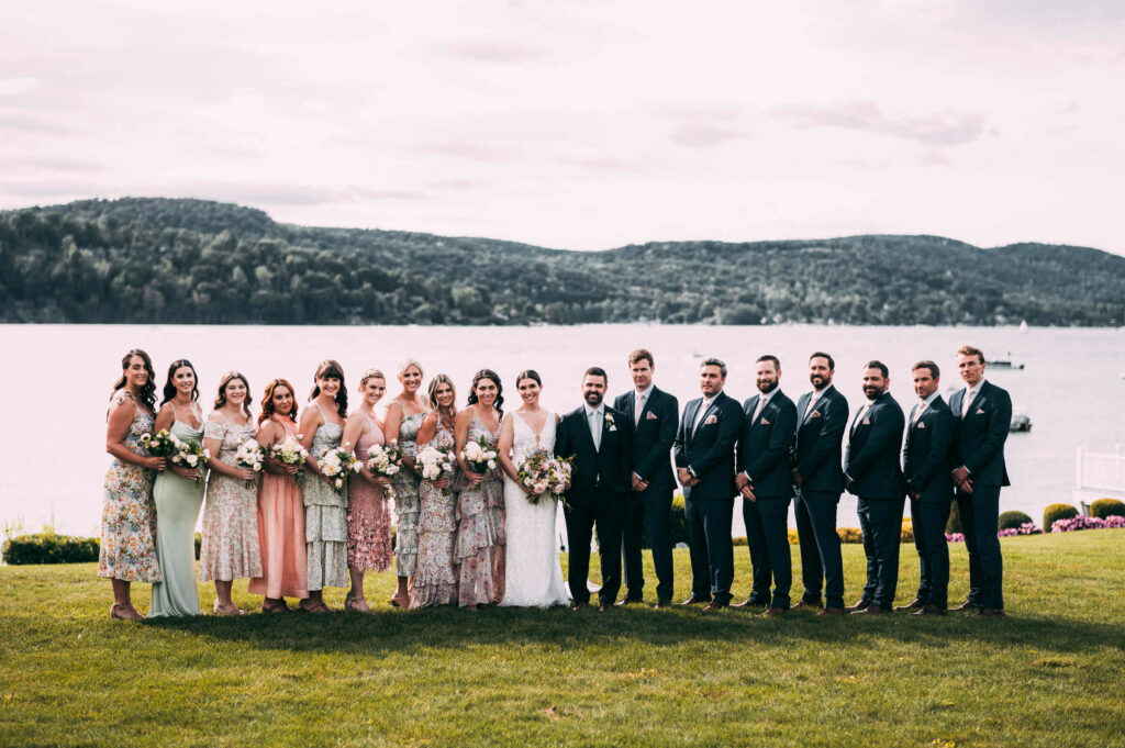 A large wedding party poses with the bride and groom during a Connecticut lake wedding.