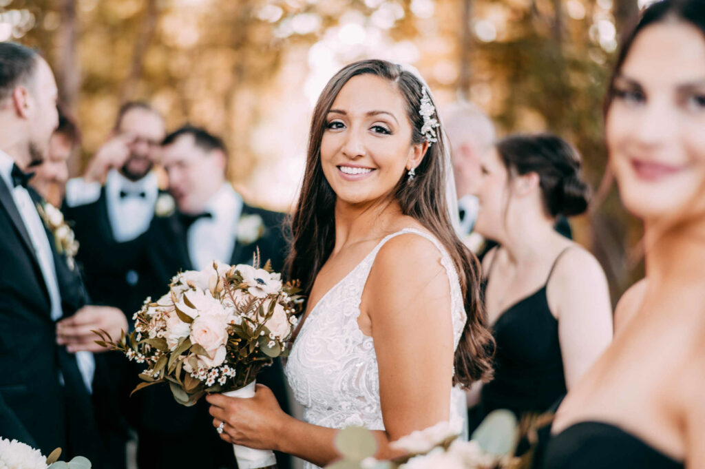 The bride smiles while holding a bouquet during her wedding at Lake of Isles.