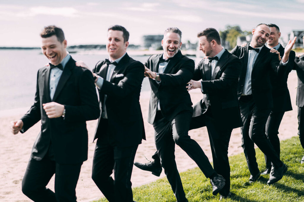 The groom and groomsmen dance and smile during his Madison, Connecticut wedding day.