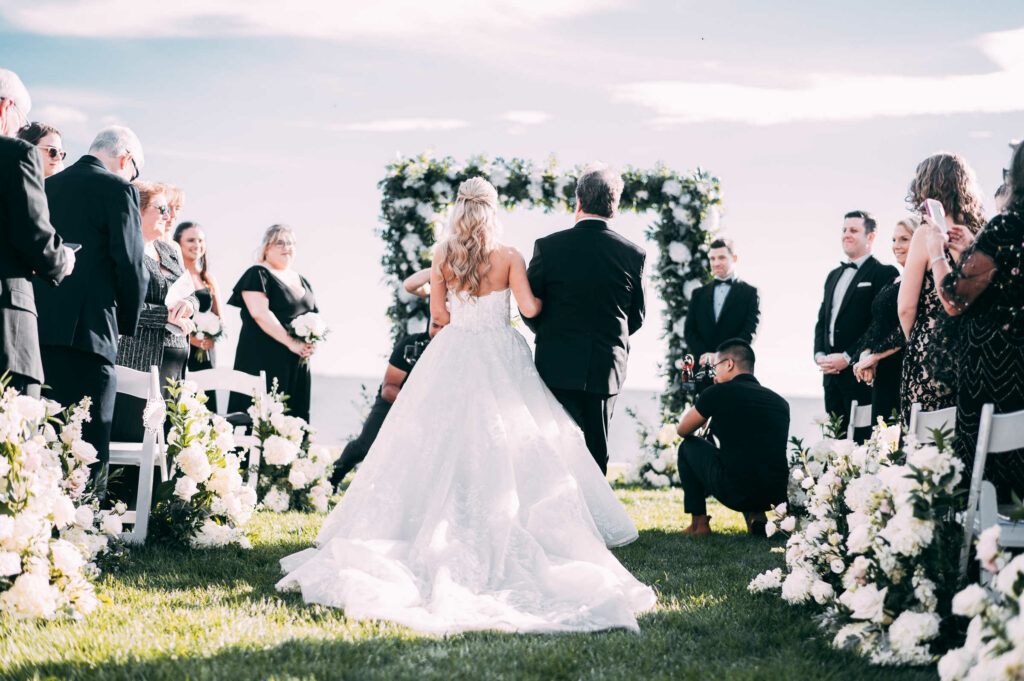 A bride is walked down the aisle during her Madison Beach Club wedding.
