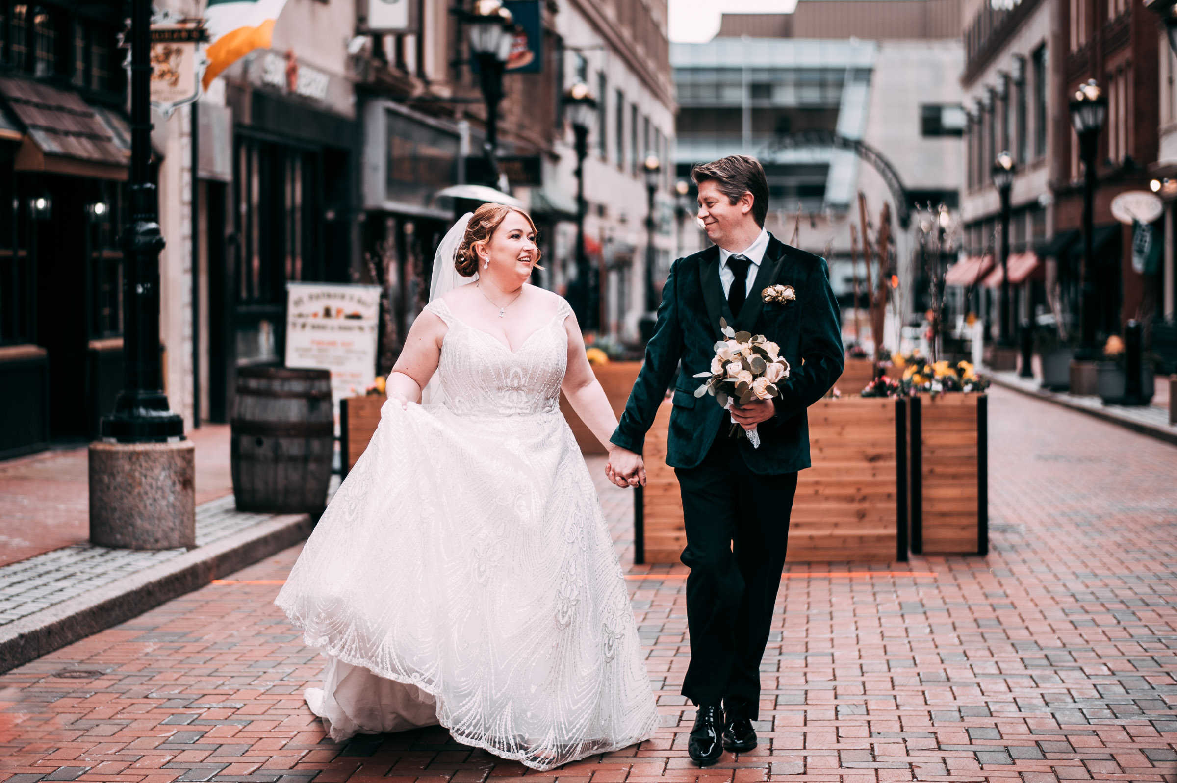 A couple holds hands and walks together outside of The Society Room, one of many city wedding venues in Connecticut.