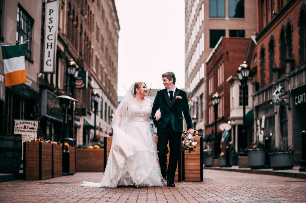 A bride and groom walk arm in arm on Pratt Street outside The Society Room of Hartford.