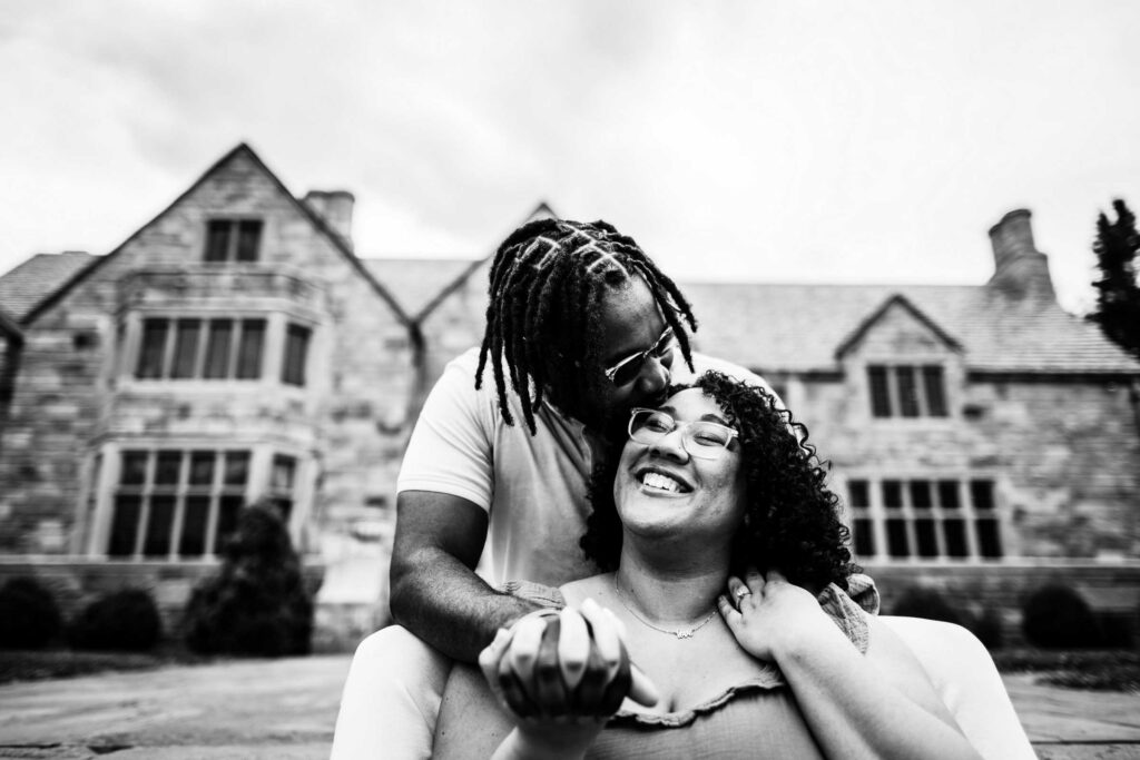 A black couple sits down and embraces in Cranbury Park, the site of Gallaher Mansion weddings in CT.