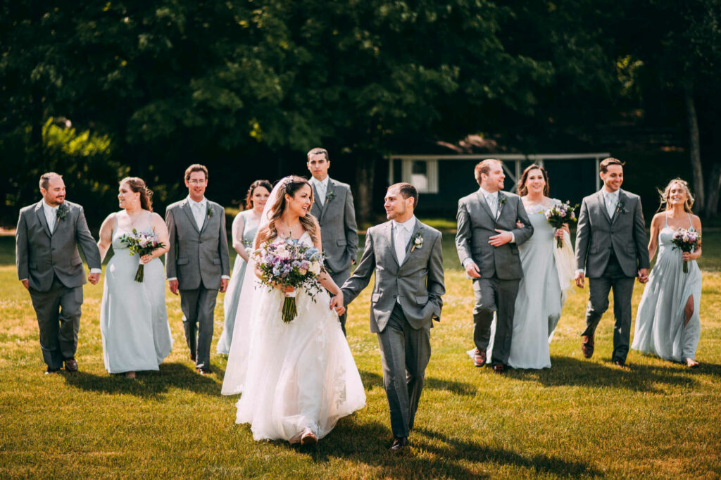 The bride and groom walk with their wedding party members during their Holiday Hill Day Camp wedding.