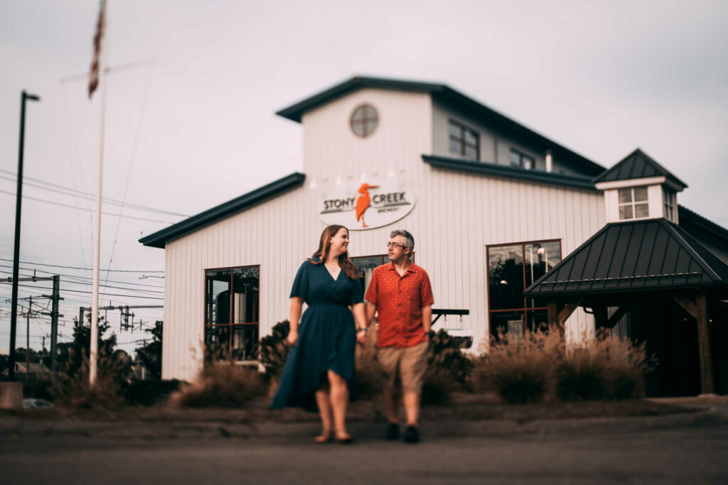 A couple holds hands and walks in front of Stony Creek, one of the better beer wedding venues in CT.