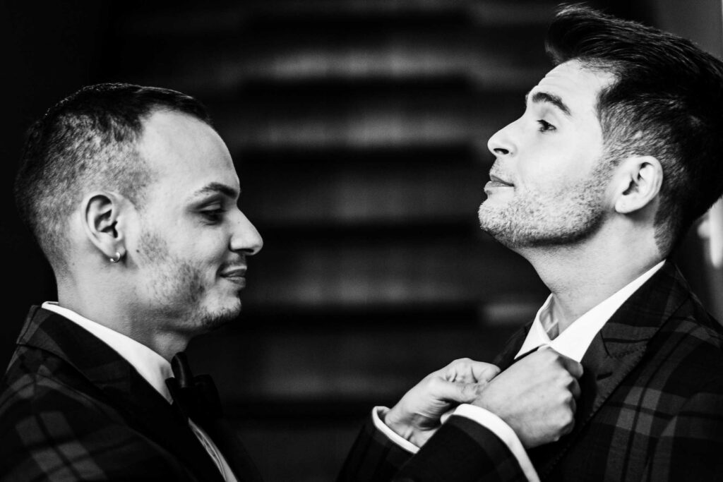 One groom adjusts the other's bowtie during their LGBTQ Connecticut wedding.