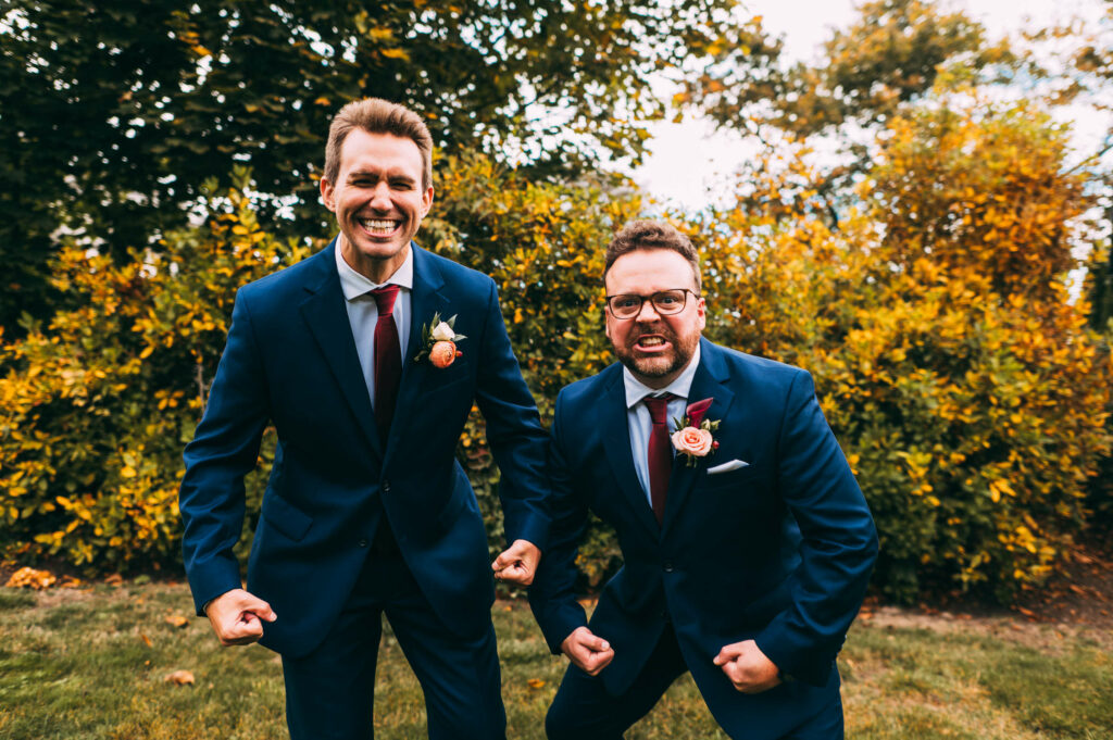 Groom and groomsman flex in blue wedding suits during his wedding at Castle Hill inn.